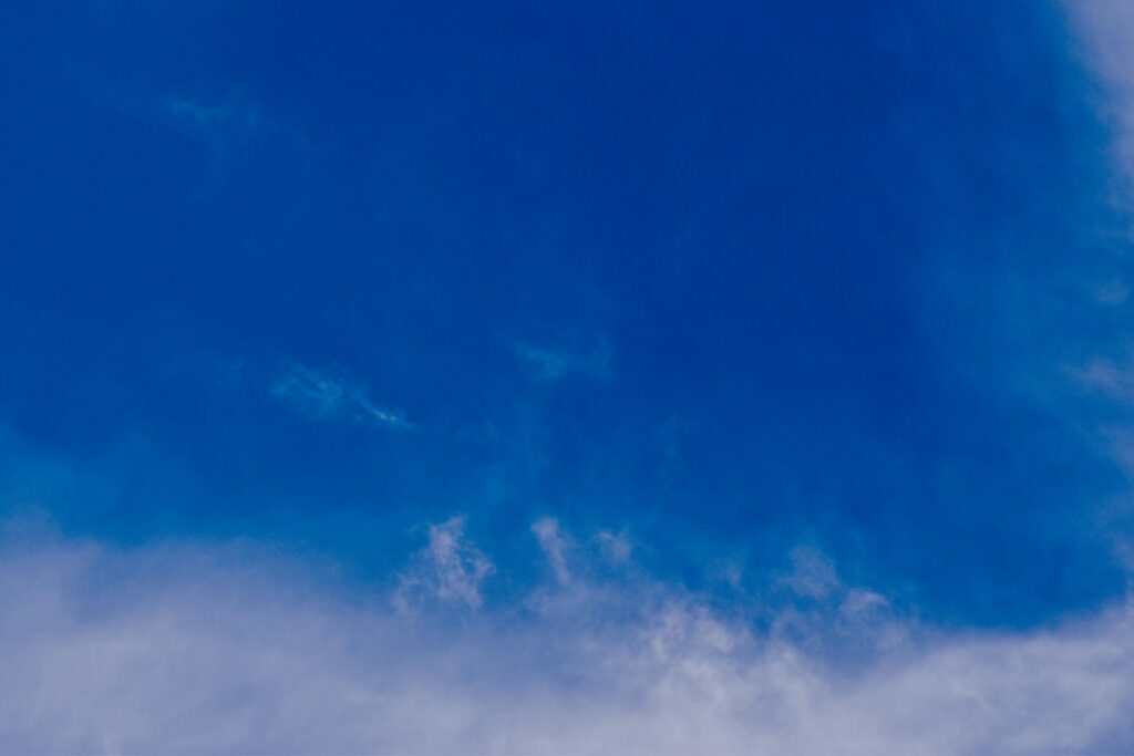 Clear blue sky with soft fluffy clouds, perfect for serene weather backgrounds.